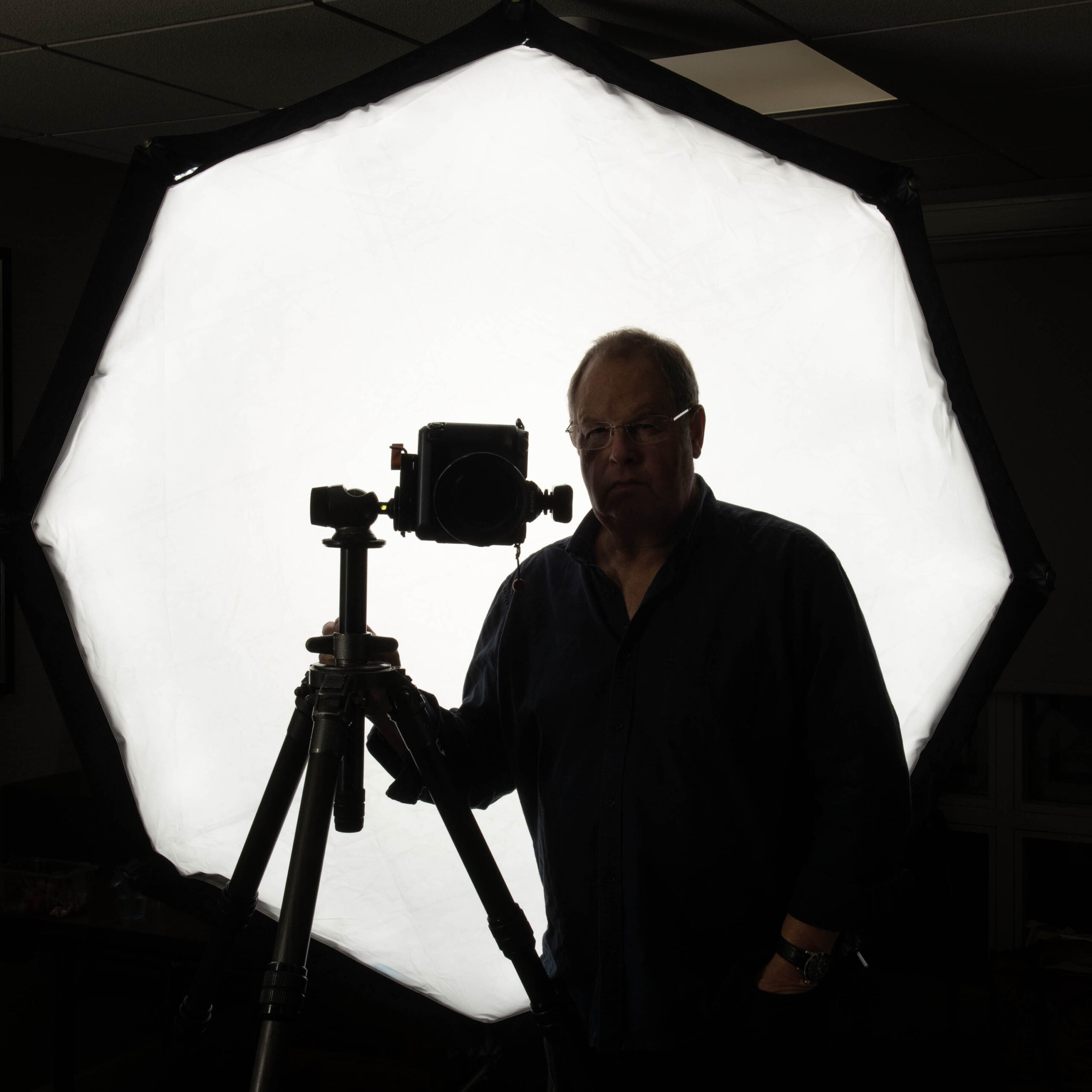 Lorentz Gullachsen with camera on tripod in sillouete with large light behind