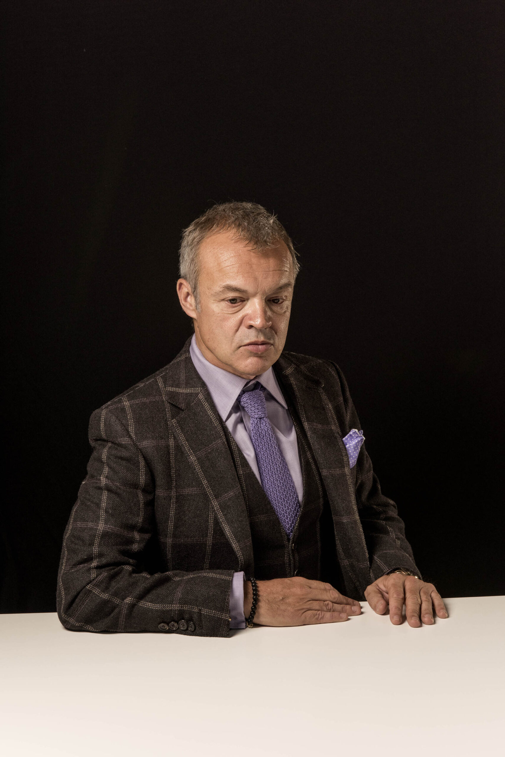 Graham Norton at white desk looking pensive