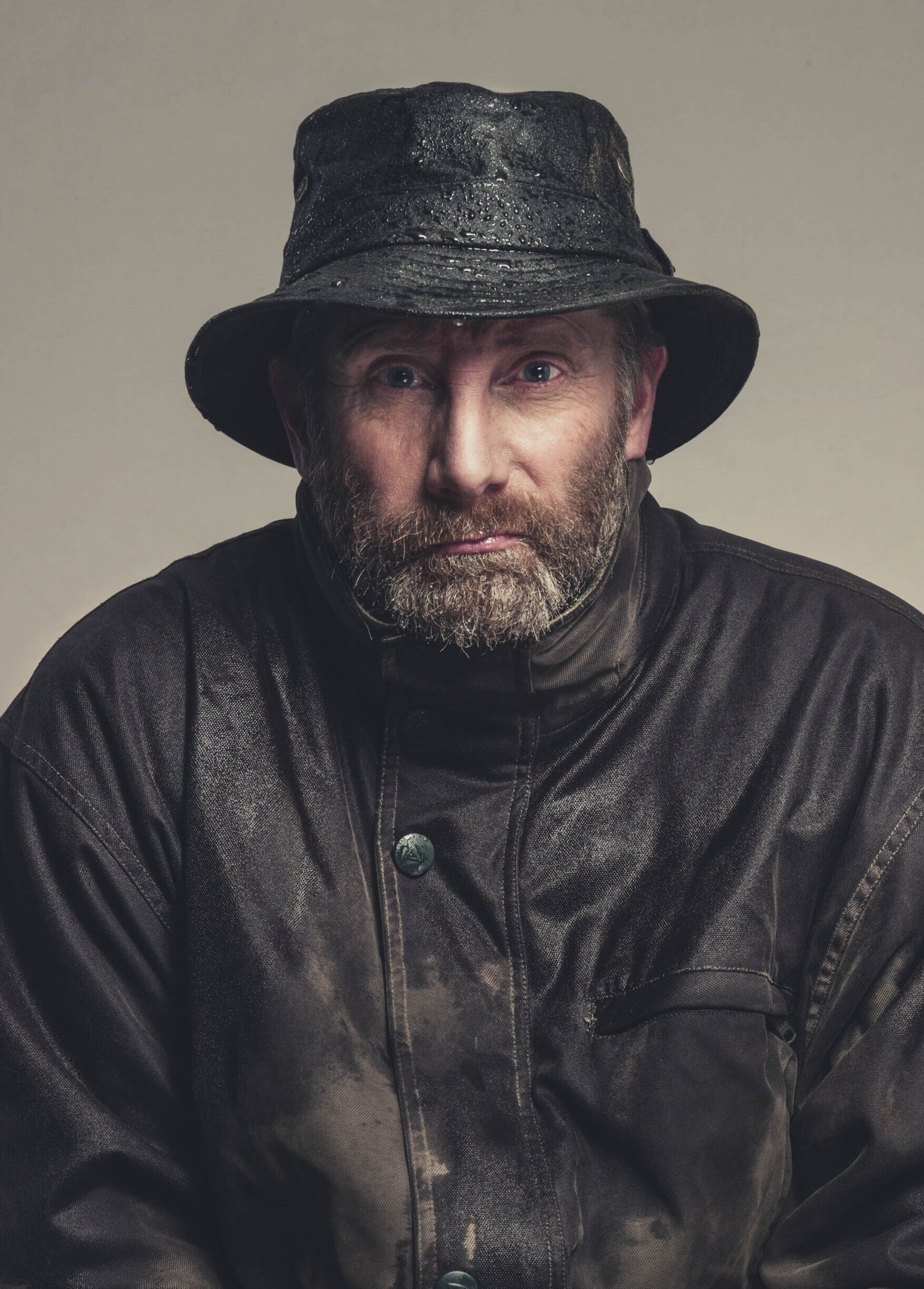 man in waterproofs and wet hat looking glum