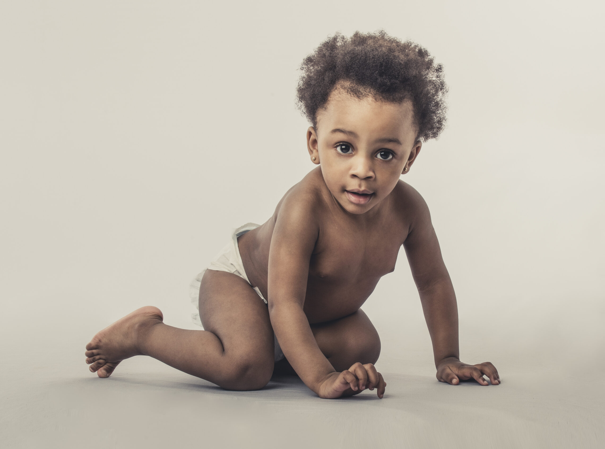 Baby in nappie on plain background looking to camera