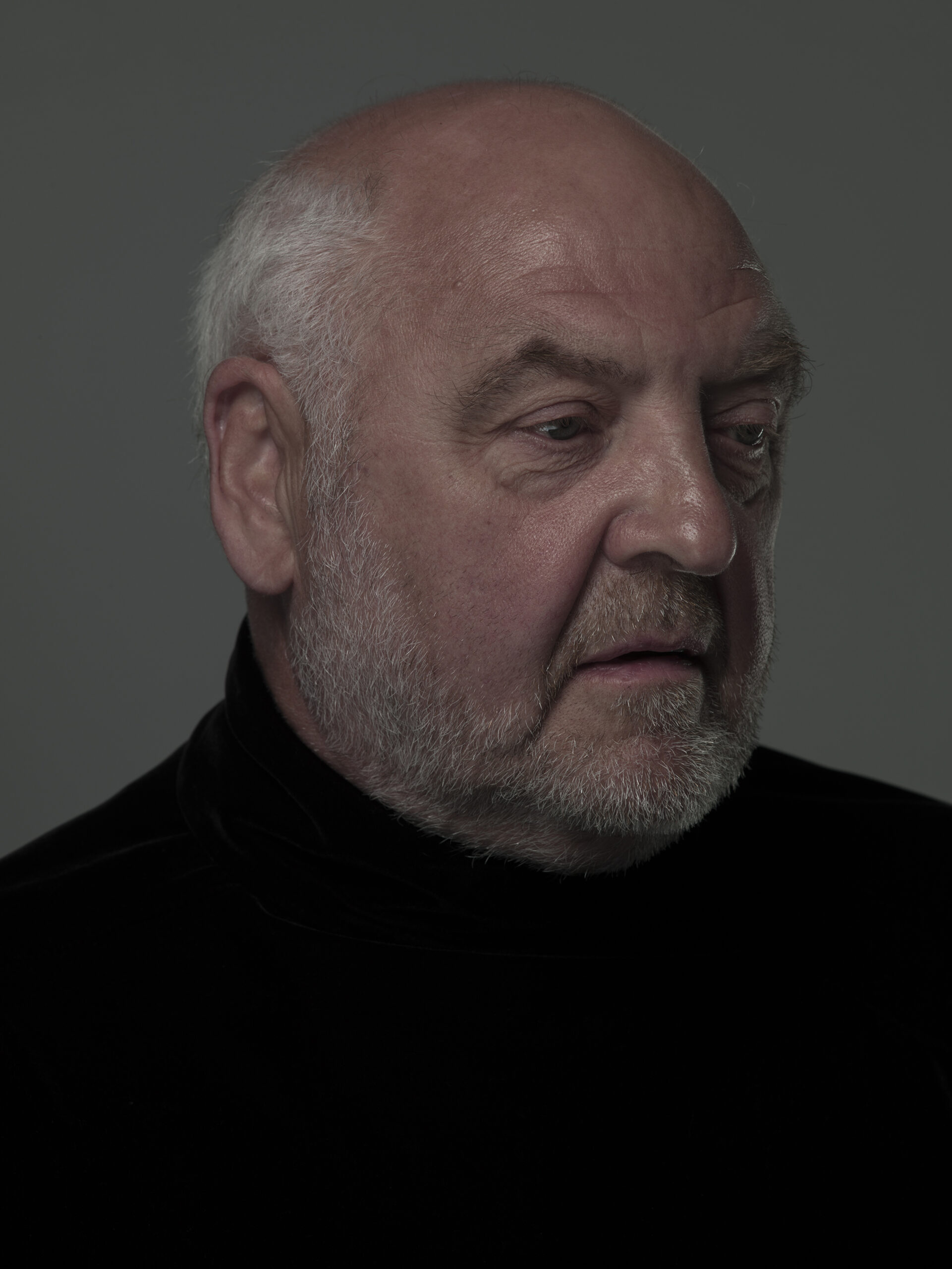 gentleman in black with dark background looking away