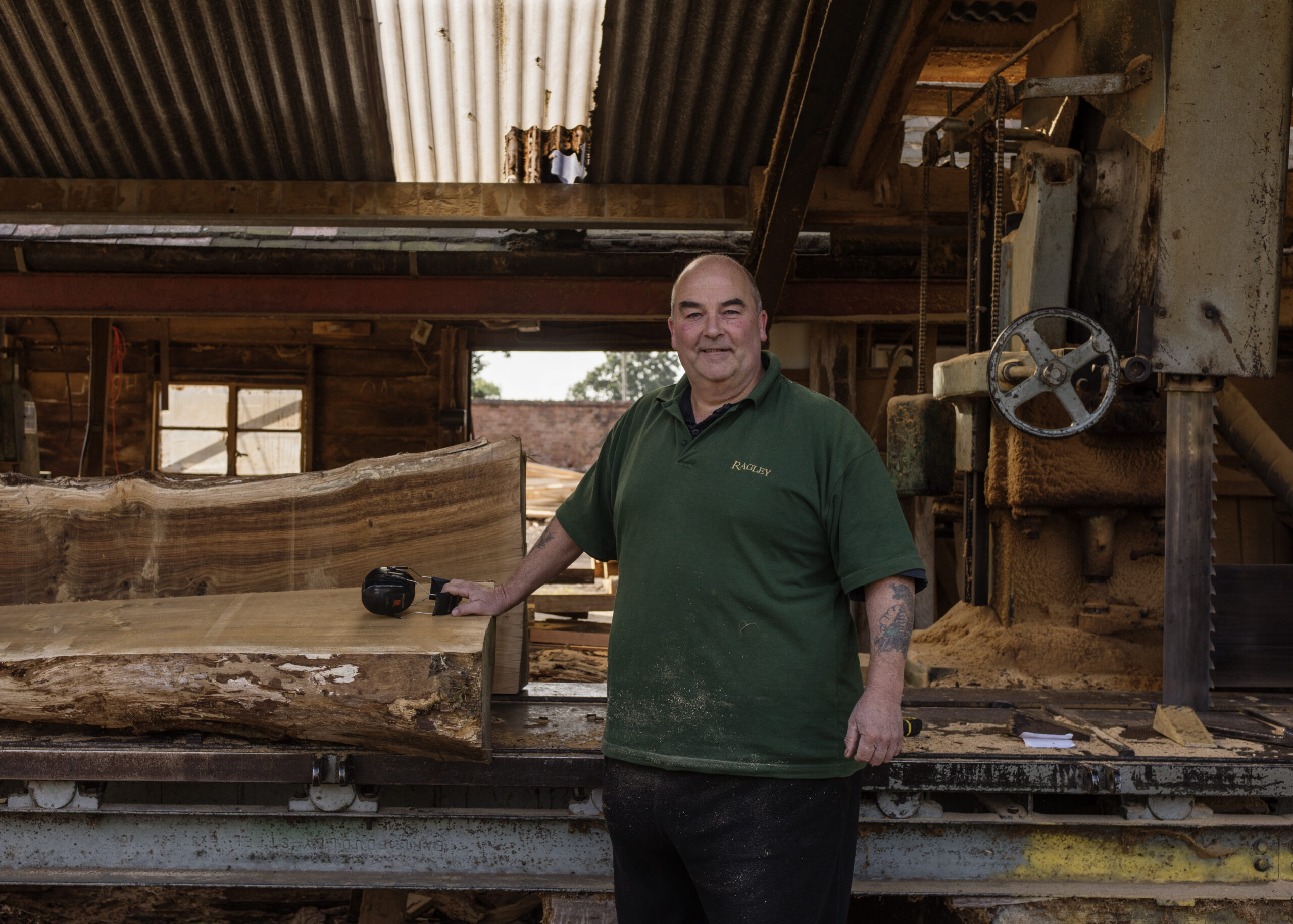 Large man in front of a saw with log in sawmill